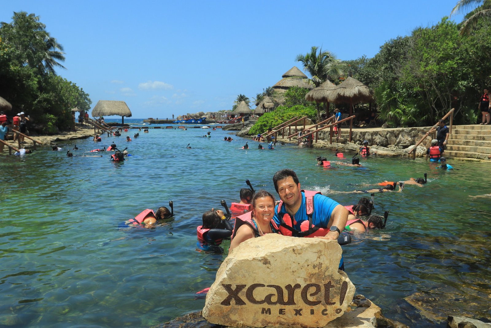 Susan and her husband at the Xcaret Mexico sign in the Riviera Maya