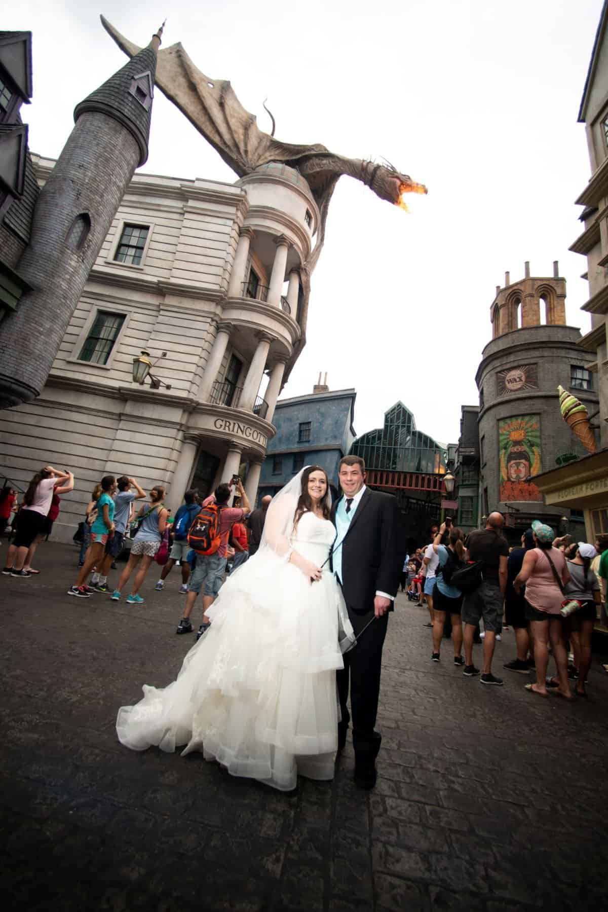 Couple in wedding attire in Diagon Alley at Universal Orlando, with the Gringotts dragon overhead